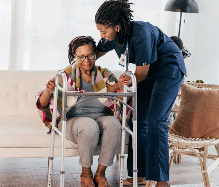 A participant with a walking frame supported in a shared living home